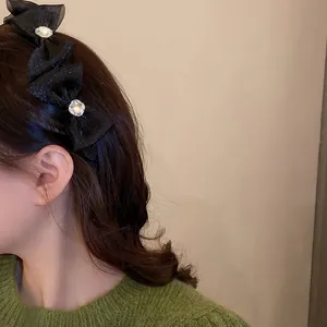 Detail of a black mesh bow headband with crystals styled on long wavy brown hair