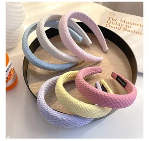 Close-up of candy-colored checkered sponge headbands on a wooden tray with hand-made labels