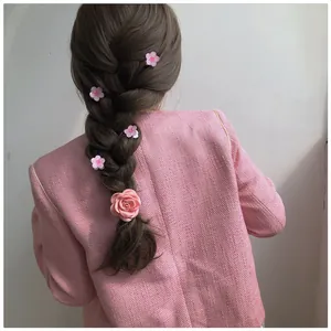 Pink camellia and rose hair clips shown on a braided hairstyle for a sweet elegant look