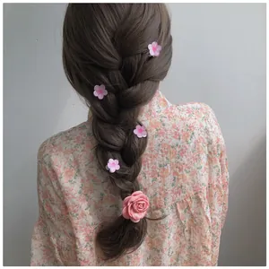 Detail view of pink fabric rose and cherry blossom hair clips worn on braided hair