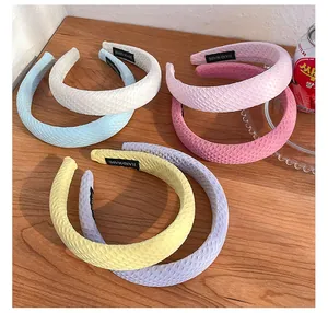 Macro detail of textured bubble grid headbands in various candy colors with handmade label