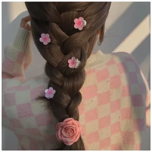 Detailed view of pink camellia hair clips and rose scrunchie styled on a braided hairstyle