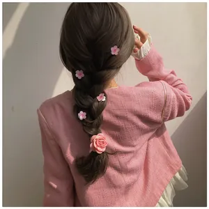 Detail of pink fabric camellia and rose hair clips styled in an elegant braided updo