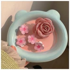 Close-up of pink satin rose hair clip and floral claw clips on a ceramic plate