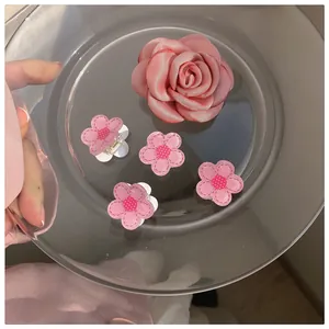 Detailed set of pink camellia and rose hair clips in a stylish transparent tray