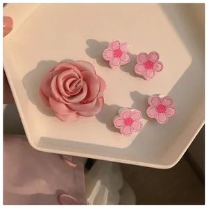 Close-up of pink satin camellia hair clip and mini floral pins in a ceramic tray