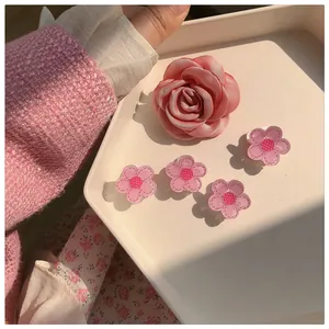 Detail of pink fabric rose and small acrylic flower clips on a cream display tray