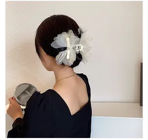 Detalle de pinza para el pelo con flor de organza crema y strass en peinado elegante