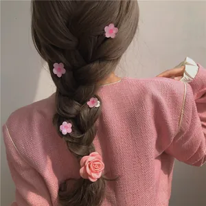 Pink camellia and rose hair clips set styled on a model's braided hair for a soft look