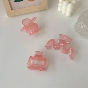 Dettaglio di fermagli per capelli rosa traslucidi a farfalla e a onde stile minimalista