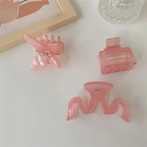 Dettaglio di tre mollette per capelli rosa traslucido a farfalla, onda e rettangolo