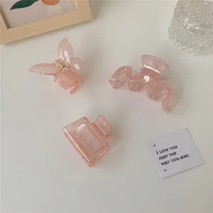 Tre fermagli per capelli rosa traslucido a forma di farfalla e onda su una scrivania