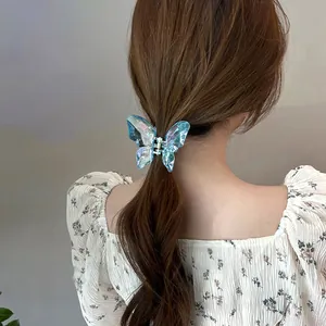 Détail d'une petite pince à cheveux papillon bleu translucide avec effet holographique