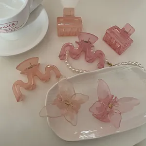 Dettaglio di fermagli per capelli a farfalla rosa traslucido e clip a onde rosa