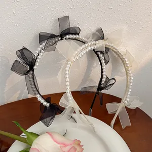 Detail of mesh bow and pearl headband placed on a white porcelain dish with a rose