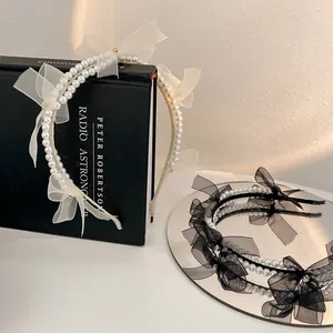 Detail of elegant mesh bow headbands with pearls in white and black styles