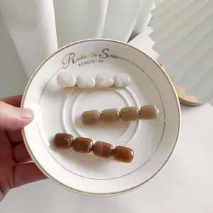 Dettaglio delle clip per capelli in acrilico marmorizzato in un vassoio di porcellana bianca