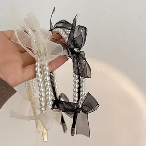 Close-up of double-row pearl headbands with mesh bows and rhinestones in black and cream