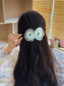 Détail d'une pince à cheveux double fleur en organza vert menthe sur cheveux ondulés