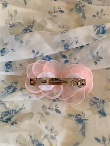 Détail de la pince à cheveux camélia en tissu rose avec barrette à ressort en métal argenté