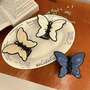 Three elegant butterfly hair claws in white, beige and blue on a vintage tray