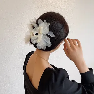 Detalle de una pinza para el pelo con flor blanca grande de organza en una modelo