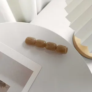 Dettaglio molletta per capelli in resina ambrata con trama marmorea su piatto bianco