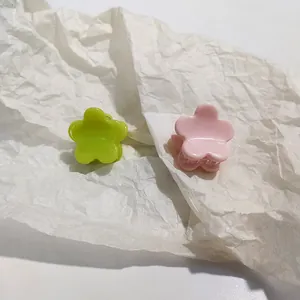 Macro view showing two small cream floral resin hair clips in green and pink pastel tones