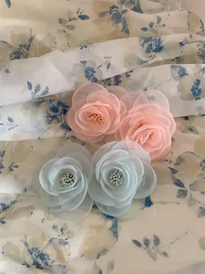Vue macro détaillée de barrettes camélia en organza rose et bleu avec centres perlés