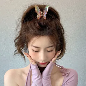 Gros plan d'une pince à cheveux papillon irisée aux facettes de cristal sur un modèle