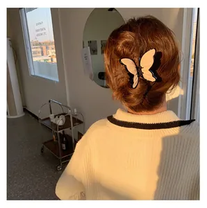 Detail shot of large cream bow hair claw clip styled in a low bun for women