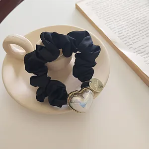Détail d'un chouchou en satin noir avec pendentif cœur irisé sur tasse à café