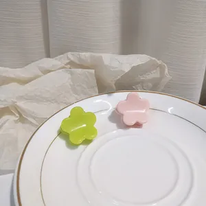 Close-up of small neon green and pink floral hair claws on a ceramic display plate