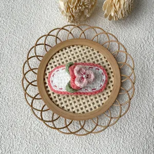 Détail d'une pince à cheveux rose au crochet faite main avec perle sur plateau bambou