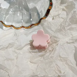 Close-up of pink flower hair claw clip on textured paper for minimalist styling