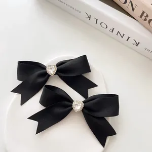 Elegante set van twee zwarte haarstrikken met hartvormige strass op wit bord