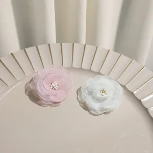 Detail of pink and white camellia hair clips with chiffon petals and pearl centers
