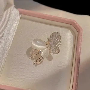Detailed macro view of silver butterfly clip with white cat-eye stones and sparkling crystals
