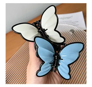 Detailed view of 3D butterfly hair claws in white and blue with black trim and metal spring