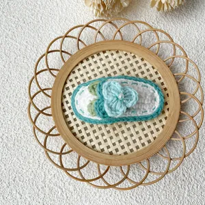 Gros plan sur pince à cheveux fleur au crochet avec perle sur plateau en osier