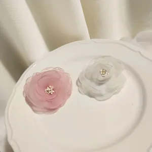Detailed close-up of pink and white layered chiffon camellia clips with faux pearl stamens