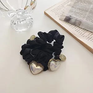Chouchou élégant en satin noir avec breloques cœur irisées et détails dorés fins