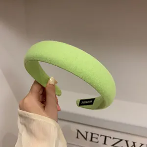Detail of handmade lime green sponge headband with knitted texture and woven label