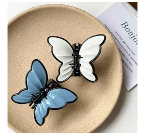 Detail of blue and white butterfly hair claws with black edges on a textured tray