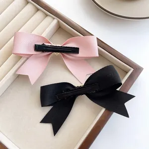 Roze en zwarte grosgrain lint strik haarspelden met metalen eendenbekclips in een display
