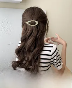 Detail of pale green acrylic oval hair clip on wavy brown hair for elegant half-up style