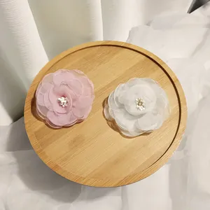 Macro shot of layered chiffon camellia hair clips with delicate bead stamen on wood