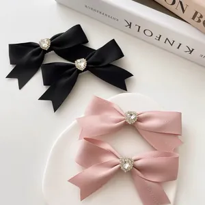 Elegante haarclips met strikken en hartvormige steentjes in zwart en roze