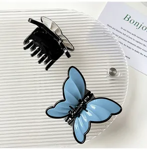 Detail view of butterfly hair claws in blue and black finish on a textured tray