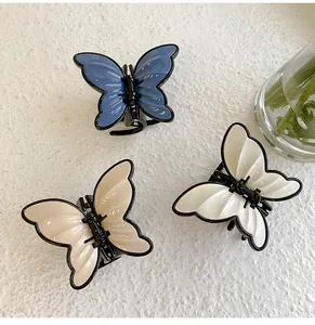Detailed view of three butterfly hair claws in navy, cream and white with black trim